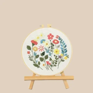 Hand-embroidered wildflower bouquet in a wooden hoop, displayed on a mini easel.