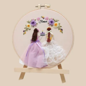 Handmade embroidery hoop featuring two girls in lace dresses holding a birthday cake under floral arch – perfect for wedding gift ideas.